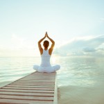 Caucasian woman practicing yoga at seashore